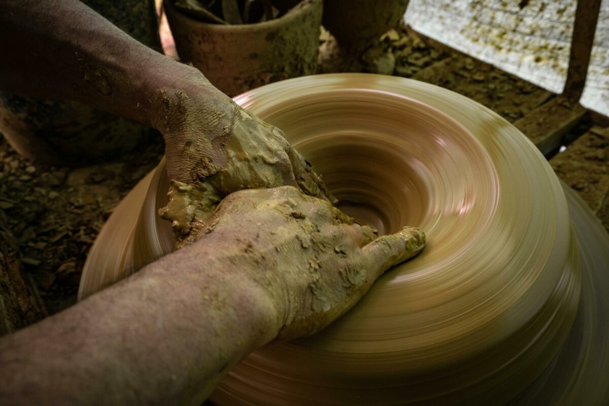 Mains d’un artisan façonnant de l’argile sur un tour de potier.