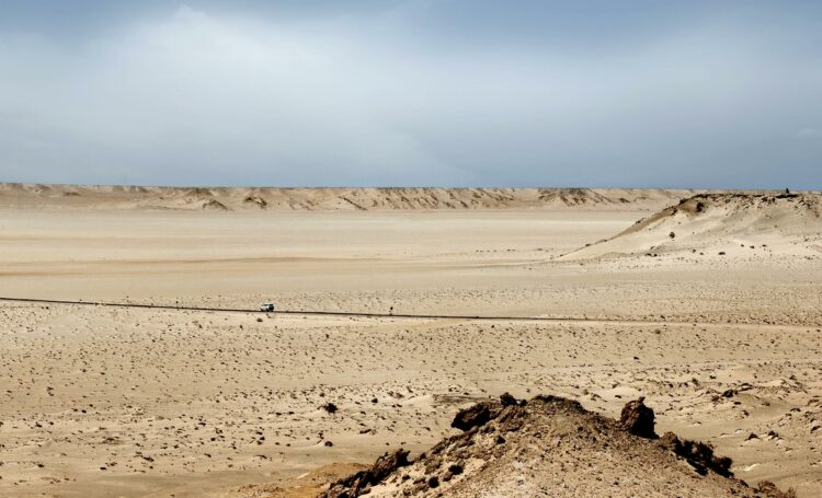 Étendue désertique à Dakhla, Maroc, avec une vue panoramique sur les dunes et une route solitaire.