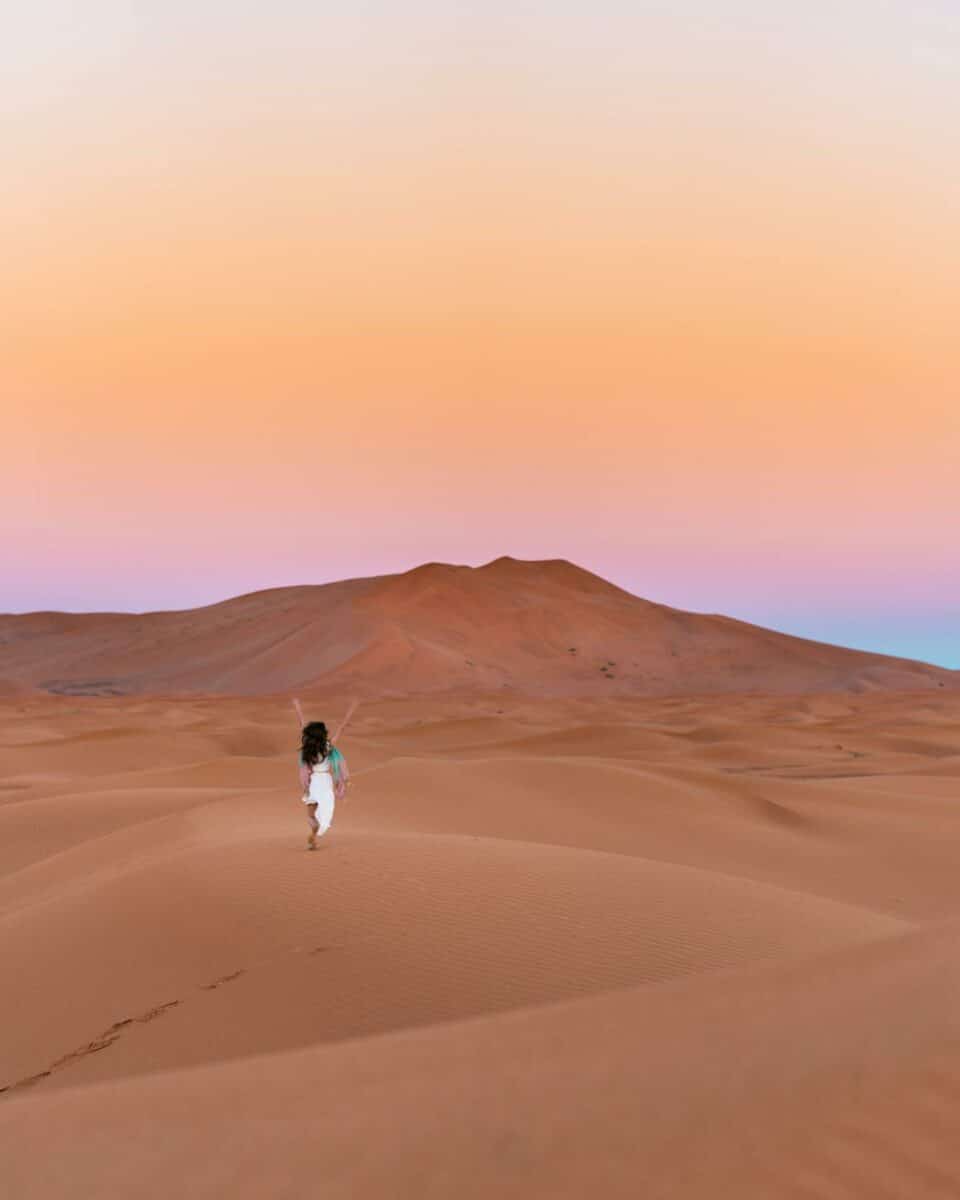 Une femme marchant seule dans les dunes au coucher du soleil à Dakhla.