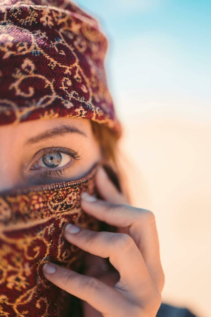 Gros plan d’une femme berbère avec un foulard traditionnel, mettant en valeur son regard intense.