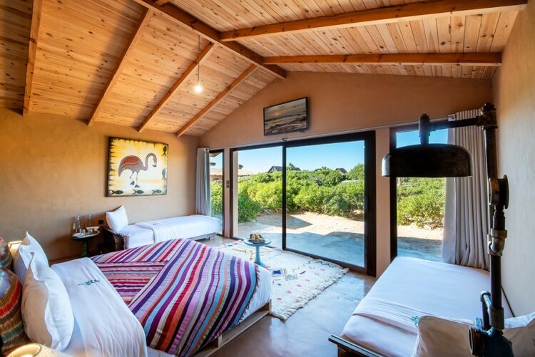 Intérieur spacieux d’un bungalow avec une décoration colorée et vue sur jardin à West Point Dakhla.